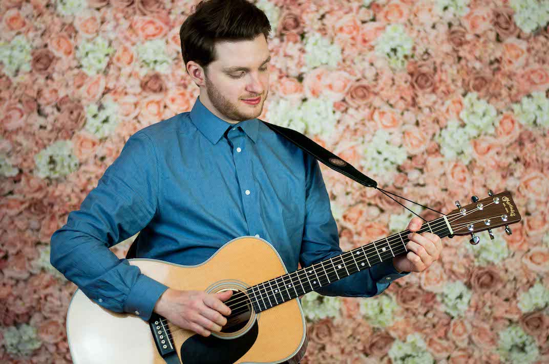 Musiker steht vor einer Blumenwand